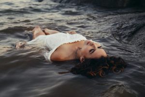 woman in white dress, laying peacefully in a stream